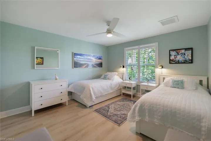 Wood-finish flooring, white ceiling fan with integrated lighting, and window with plantation shutters