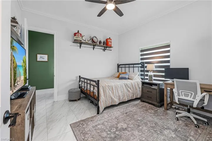 Bedroom featuring ornamental molding, a ceiling fan, and light floors