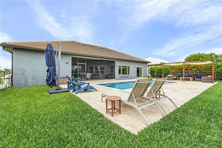 Rear view of house featuring a yard, a patio area, stucco siding, and a tiled roof