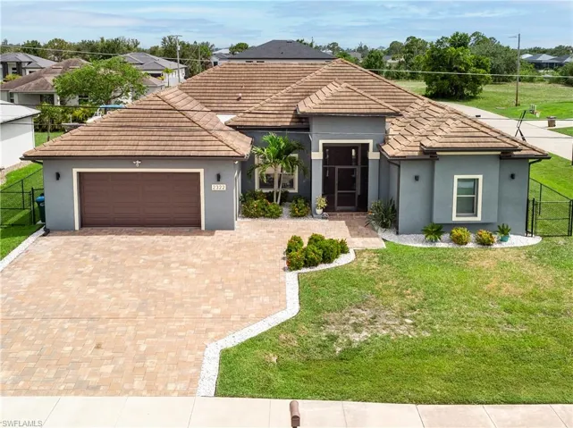 View of front of house featuring an attached garage, decorative driveway, stucco siding, and a tiled roof