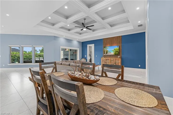 Dining room with coffered ceiling, beam ceiling, ceiling fan, light tile patterned floors, and crown molding