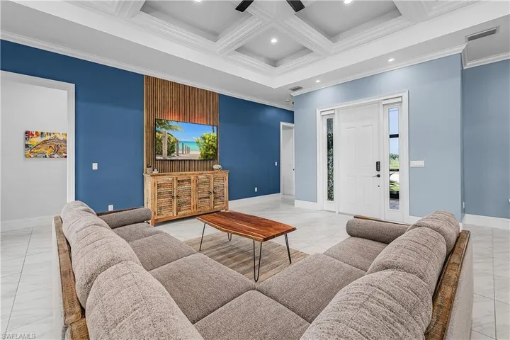 Living room featuring coffered ceiling, crown molding, beam ceiling, recessed lighting, and a ceiling fan