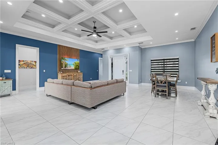 Living room with ceiling fan, ornamental molding, recessed lighting, coffered ceiling, and beamed ceiling