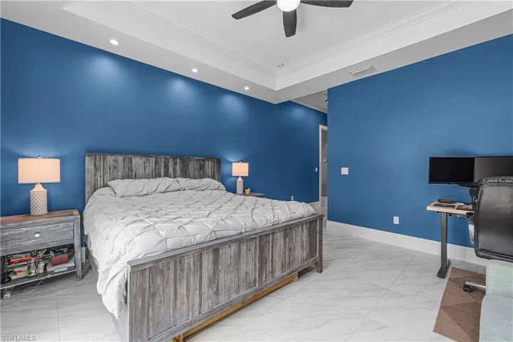 Primary bedroom with crown molding, light flooring, recessed lighting, and a ceiling fan