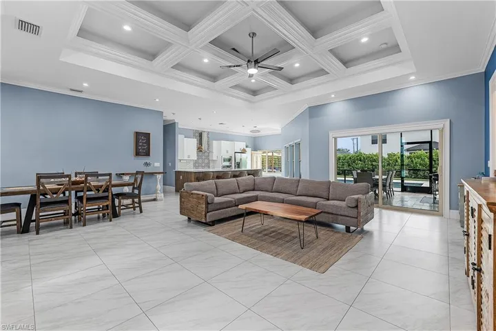Living room with ceiling fan, coffered ceiling, recessed lighting, ornamental molding, and beamed ceiling