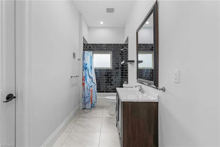 Bathroom featuring vanity, shower / tub combo with curtain, and light floors