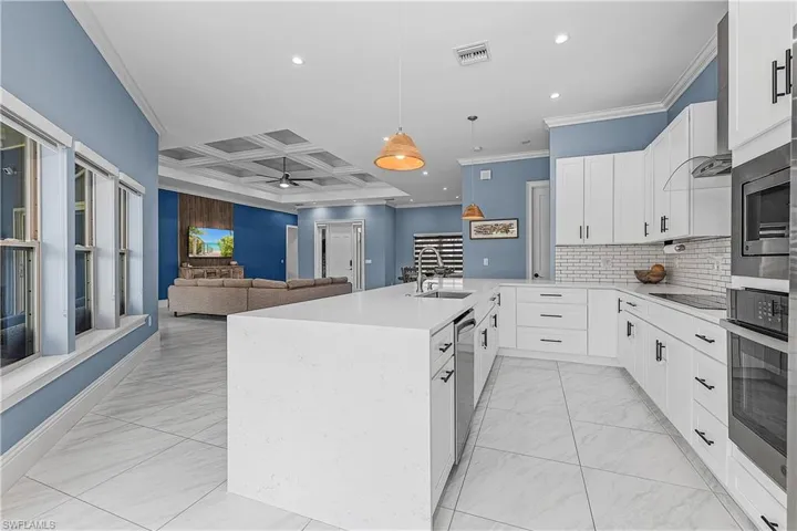 Kitchen with white cabinetry, light stone counters, recessed lighting, ornamental molding, and coffered ceiling