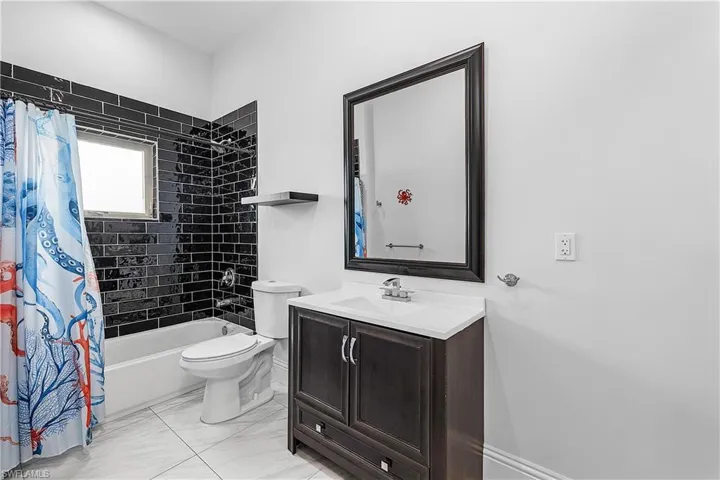 Full bathroom with vanity, shower / bathtub combination with curtain, and light floors