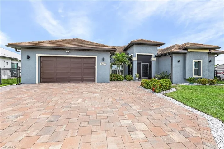 Front of home with stucco siding, decorative driveway, a garage, a front lawn, and a tile roof