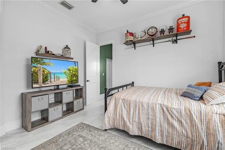 Bedroom featuring crown molding, light flooring, and a ceiling fan