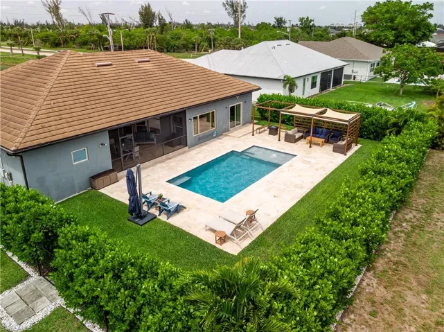 View of swimming pool featuring a patio, an outdoor area, a lawn, and a screened lanai