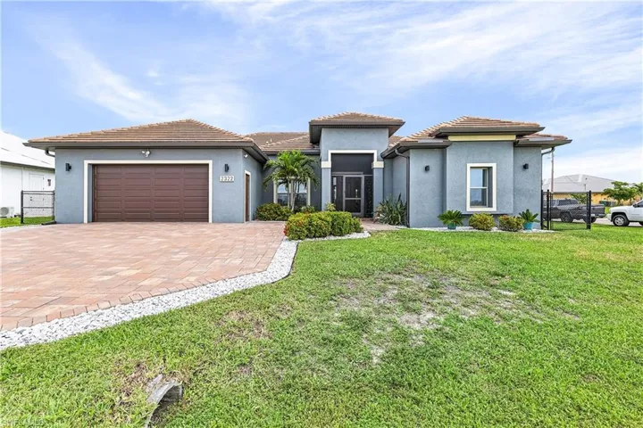 Front of house featuring stucco siding, a front lawn, decorative driveway, and a garage