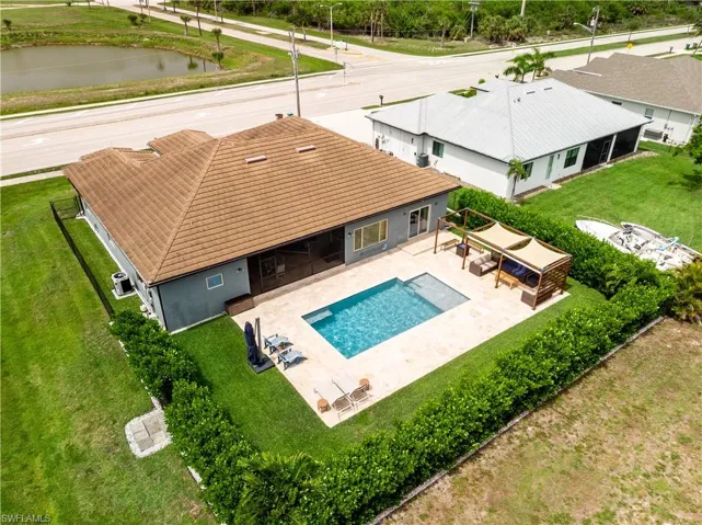 View of pool with a patio area, a lawn, and screened lanai