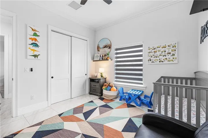 Bedroom with crown molding, a closet, light flooring, and a ceiling fan