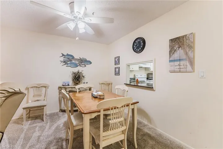 Carpeted dining space featuring a textured ceiling and a ceiling fan