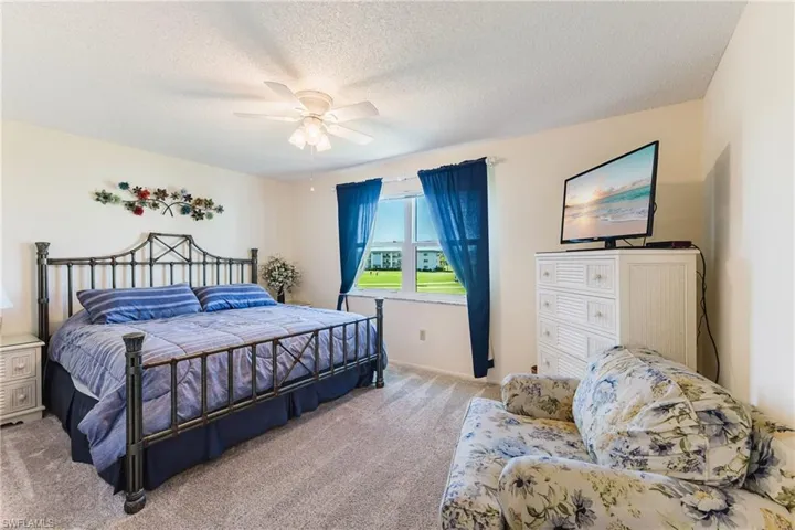 Carpeted bedroom with a ceiling fan and a textured ceiling