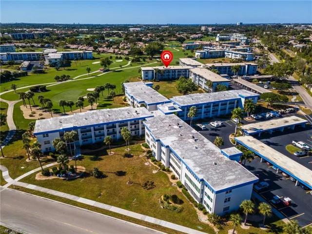 Drone / aerial view of apartment complex and a golf course