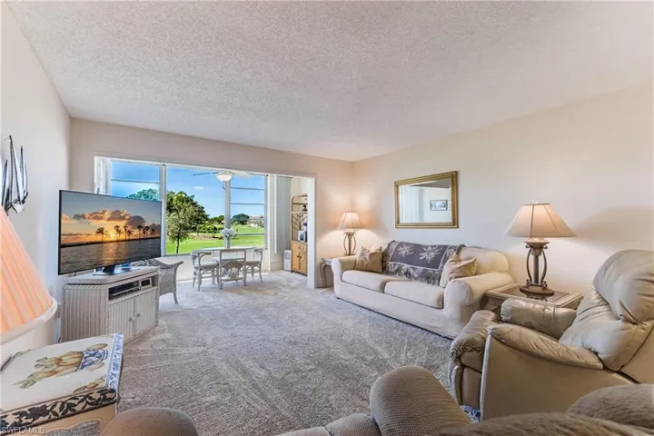 Living room featuring carpet flooring, a textured ceiling, and a ceiling fan