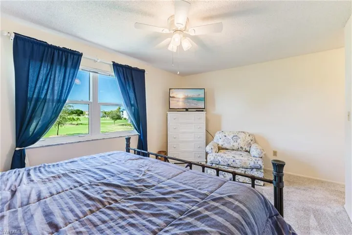 Carpeted bedroom with a textured ceiling and ceiling fan