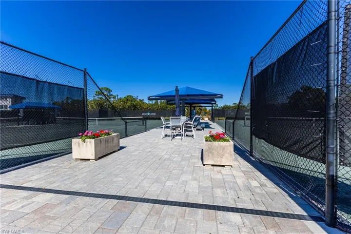 View of community with outdoor dining space, a tennis court, and a patio