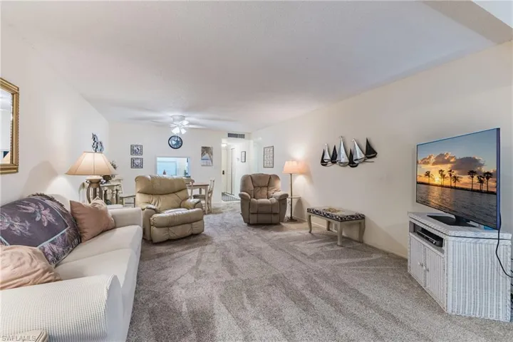 Carpeted living area featuring a ceiling fan