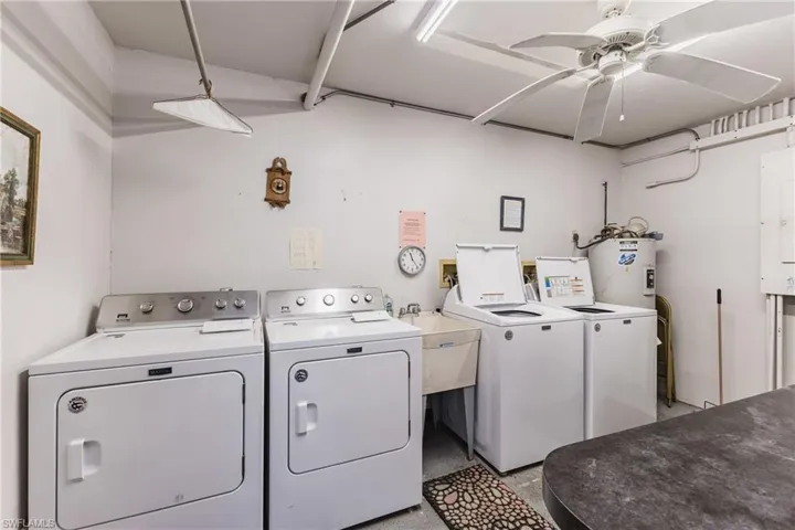Laundry room featuring washing machine and dryer, water heater, a ceiling fan, and electric panel