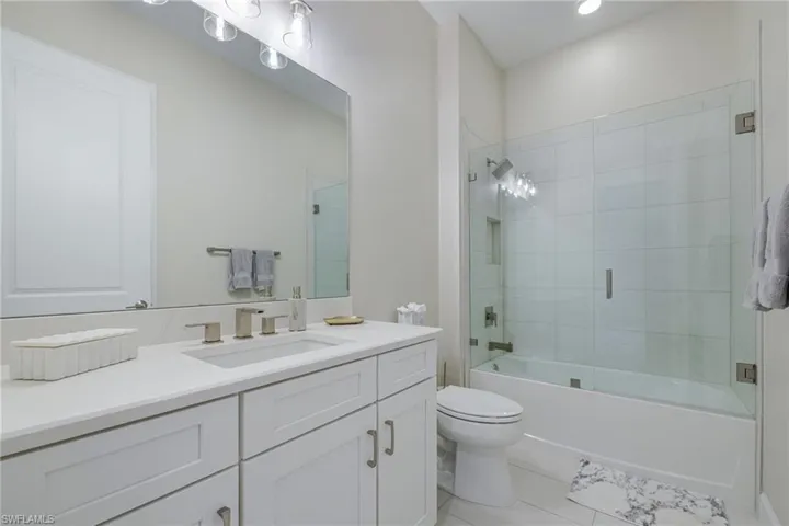 Bathroom with vanity, bath / shower combo with glass door, and light tile patterned floors