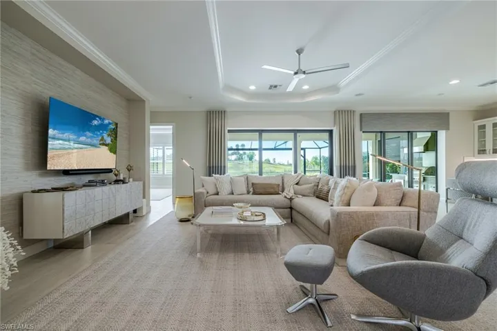 Living area featuring ornamental molding, wood finished floors, ceiling fan, recessed lighting, and a tray ceiling