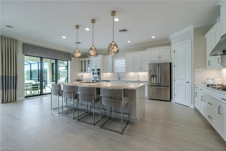 Kitchen with hanging light fixtures, crown molding, a kitchen breakfast bar, appliances with stainless steel finishes, and a center island
