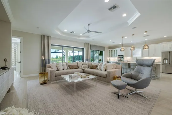 Living room with plenty of natural light, crown molding, a ceiling fan, a tray ceiling, and light wood-style floors