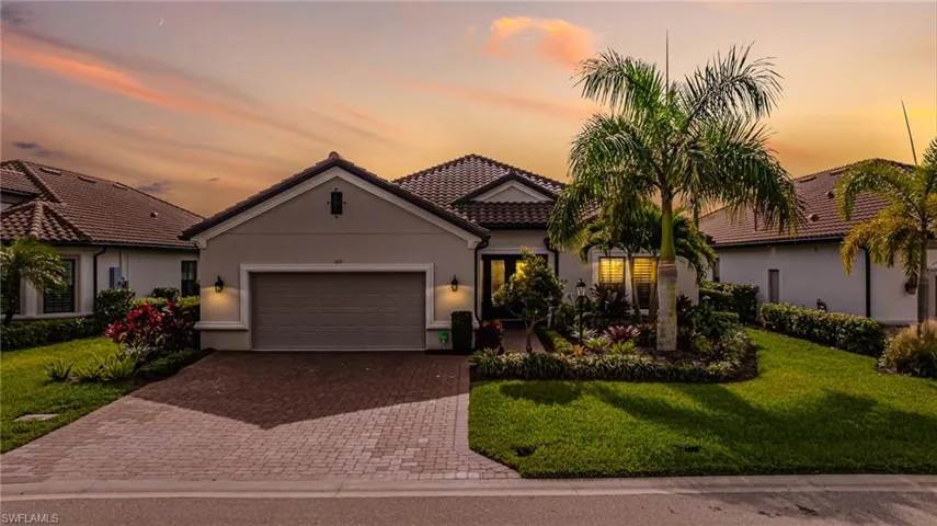 Mediterranean / spanish-style home featuring a yard, stucco siding, decorative driveway, a garage, and a tiled roof