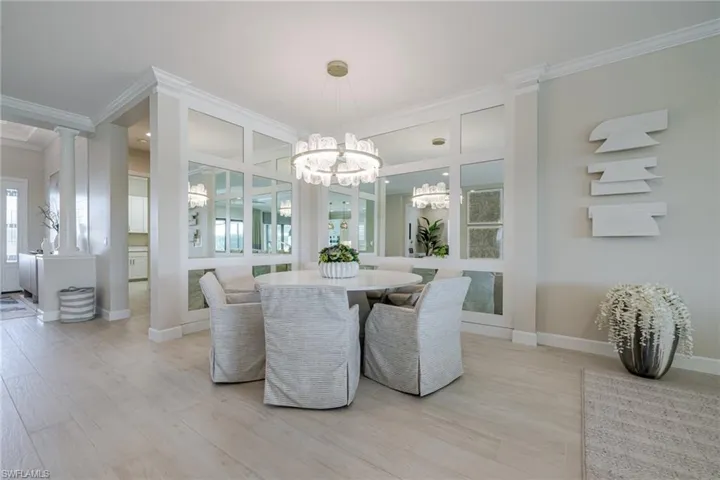 Dining space featuring ornamental molding, light wood finished floors, decorative columns, and a chandelier