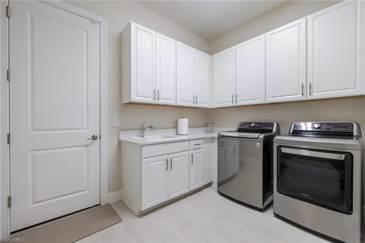 Laundry room featuring washing machine and dryer, cabinet space, and light wood-style floors
