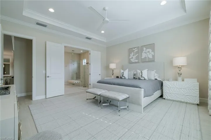 Bedroom featuring a ceiling fan, a tray ceiling, recessed lighting, connected bathroom, and crown molding