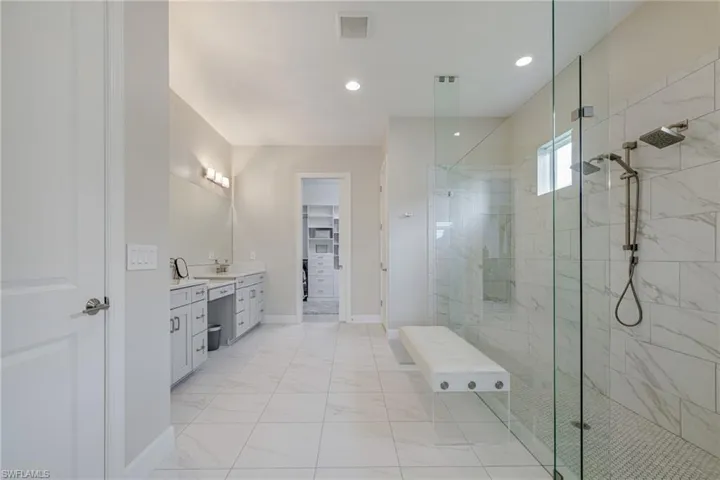Full bathroom with a walk in shower, a walk in closet, vanity, recessed lighting, and light marble finish floors