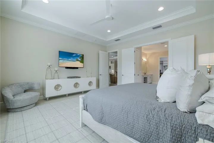 Bedroom featuring recessed lighting, a ceiling fan, ensuite bath, and a raised ceiling