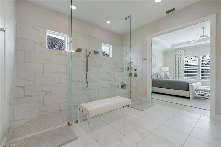 Ensuite bathroom featuring a walk in shower, ornamental molding, recessed lighting, marble finish floors, and ceiling fan