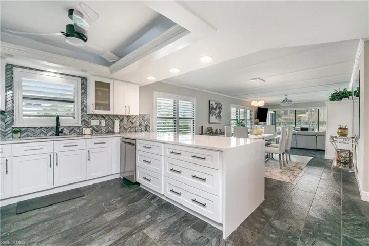 Kitchen featuring a ceiling fan, crown molding, white cabinetry, glass insert cabinets, and plenty of natural light