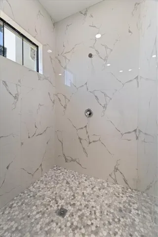 Full bathroom with a marble finish shower