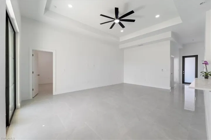 Unfurnished room with a tray ceiling, recessed lighting, baseboards, and ceiling fan