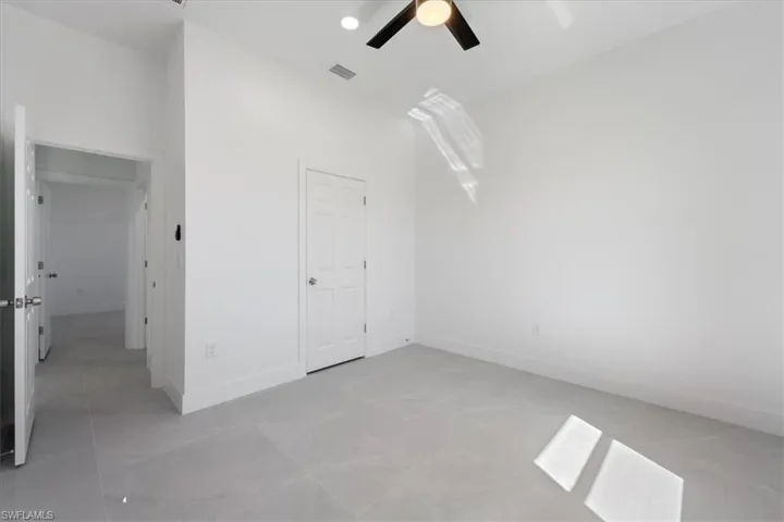 Unfurnished bedroom featuring visible vents, ceiling fan, baseboards, and a towering ceiling