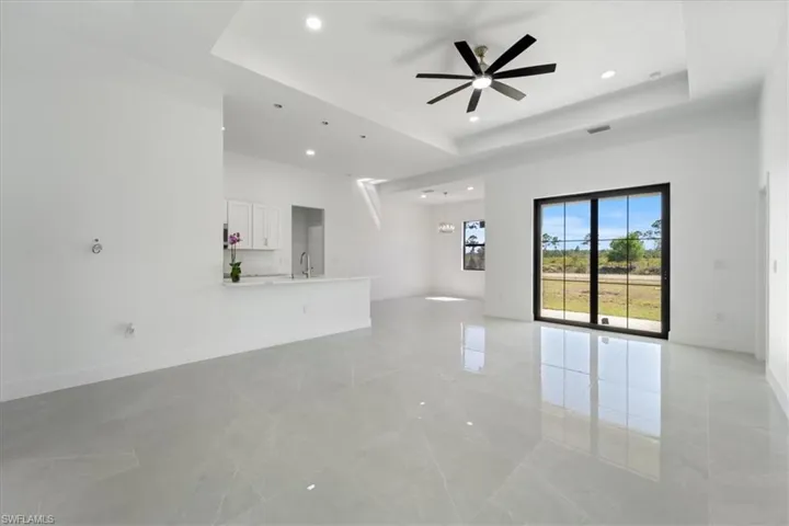 Unfurnished living room with baseboards, a ceiling fan, and a tray ceiling
