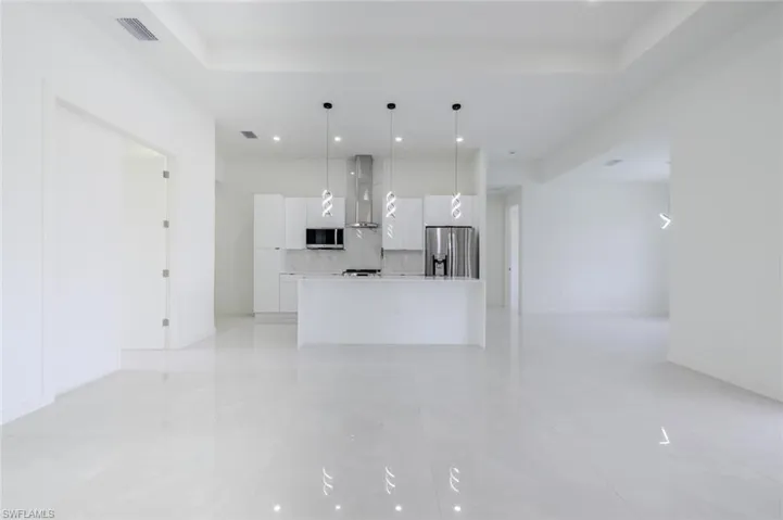 Unfurnished living room featuring a tray ceiling, recessed lighting, and light tile patterned floors