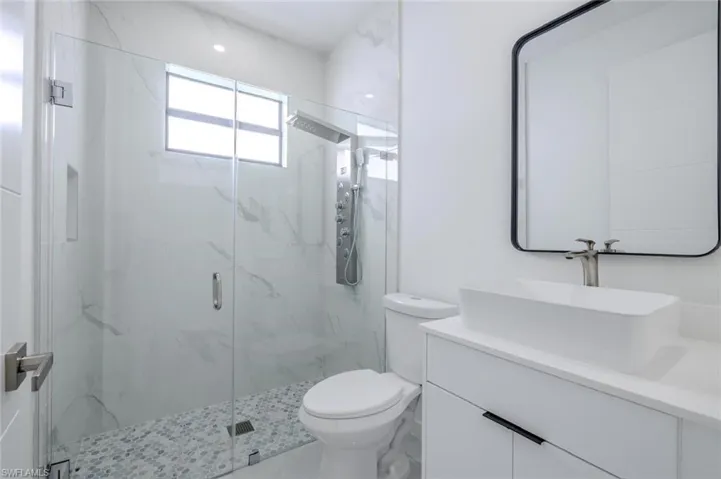 Full bath featuring vanity and a marble finish shower