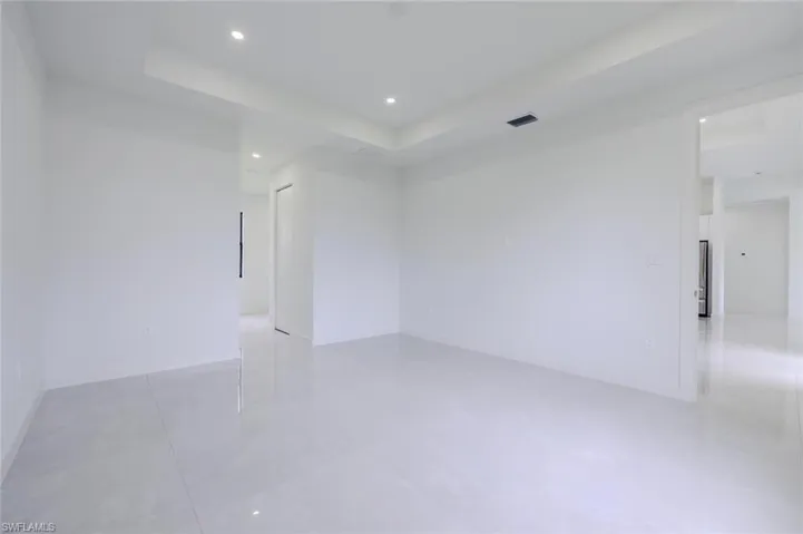 Empty room featuring a tray ceiling, recessed lighting, and light tile patterned floors