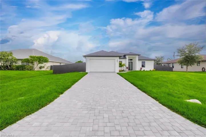 View of front of home with decorative driveway, an attached garage, and stucco siding