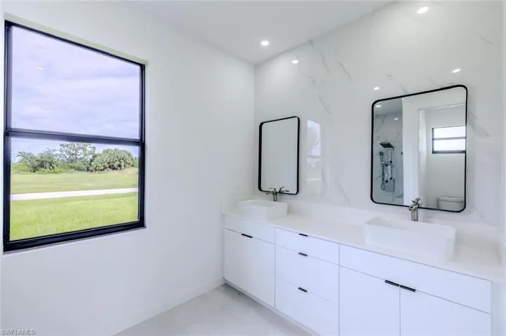 Full bathroom featuring double vanity, a marble finish shower, light tile patterned floors, and recessed lighting