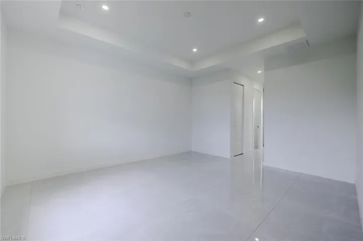 Empty room featuring a raised ceiling and recessed lighting