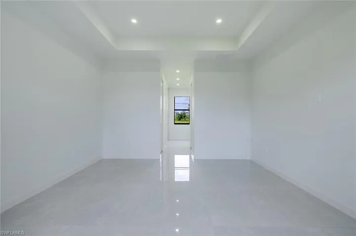 Unfurnished room with a raised ceiling, recessed lighting, and light tile patterned floors