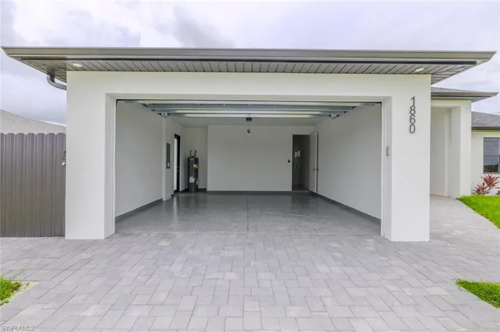 Garage featuring decorative driveway and water heater